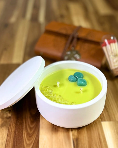 vela nueva semilla con cuarzo verde y chips de cuarzo blanco en cuenco blanco con tapa sobre mesa de madera