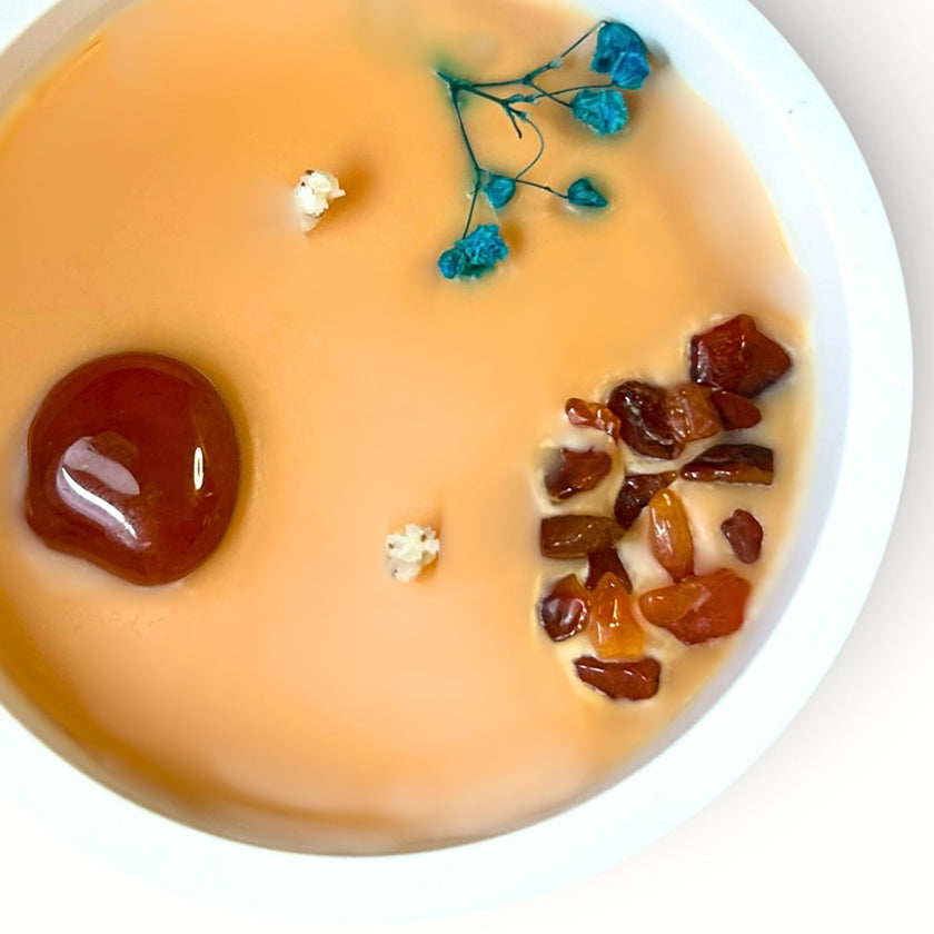 detalle de vela aromática con cornalina natural y chips minerales para ritual de enraizamiento