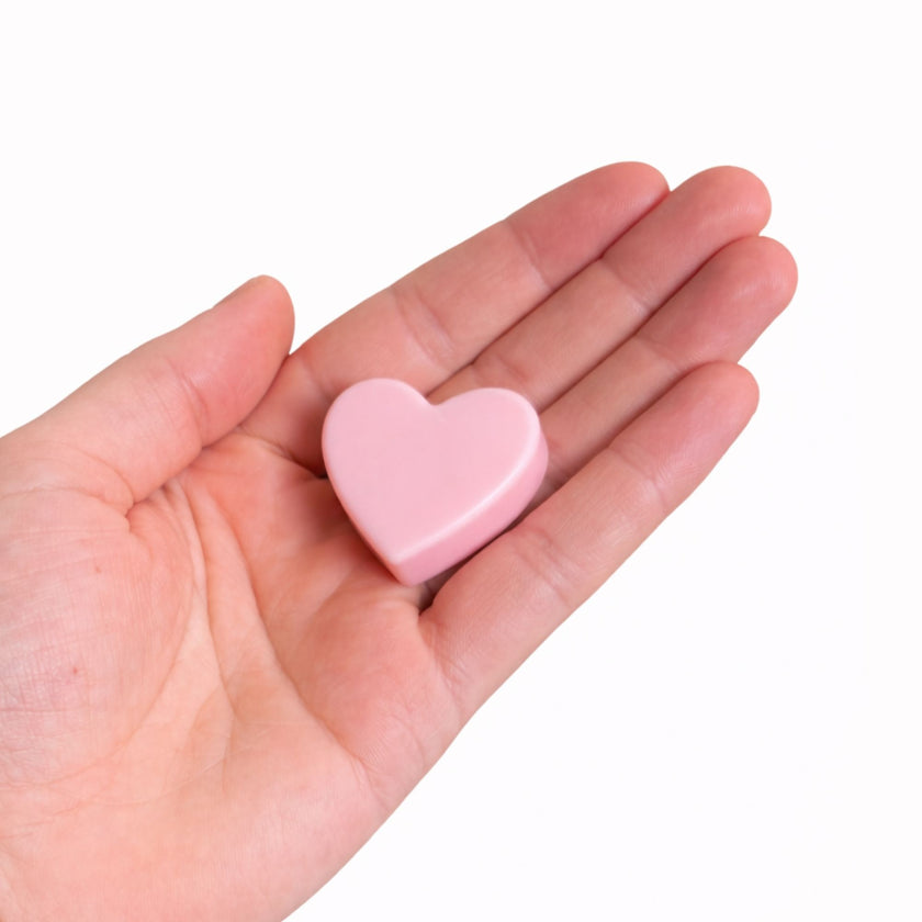 Corazón de cera rosa Abrazo del Alma sostenido en la mano, símbolo de amor propio y ternura.